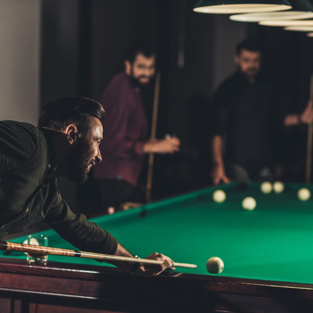 company of successful handsome men playing in pool at bar